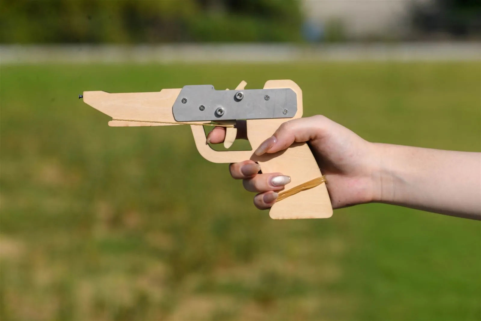 木でできた4連射ゴム銃「ツクルシューター」を手に持っている写真